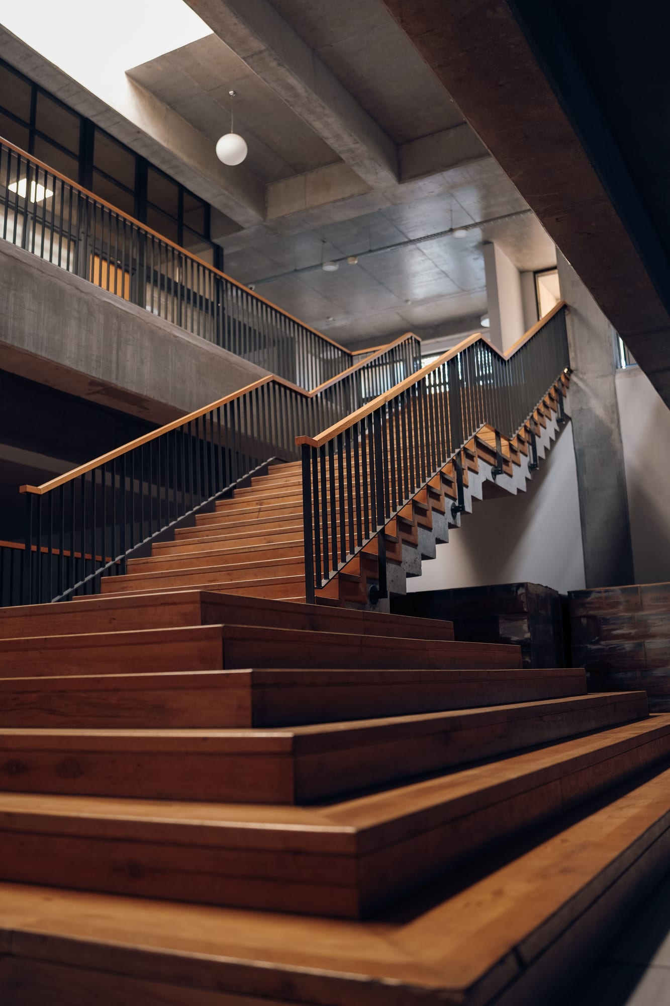 Vom Schreiner gebaute Holztreppe mit schwarzem Metallgeländer im Treppenhaus