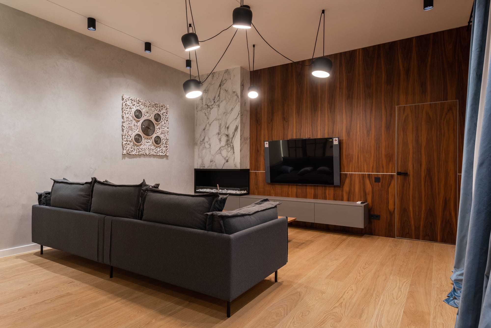 Vom Schreiner gefertigte Holz-Wandverkleidung als TV-Wand in einem Wohnzimmer mit heller Sitzecke